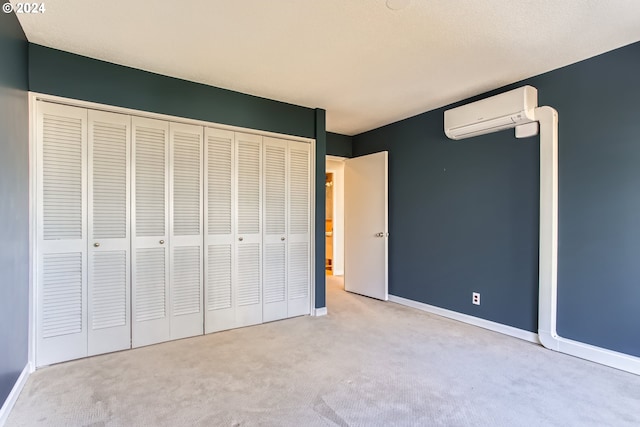 unfurnished bedroom with a wall mounted AC, light carpet, and a closet