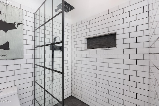 bathroom featuring tiled shower and toilet