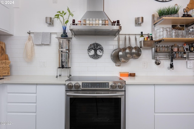 kitchen with tasteful backsplash, white cabinetry, stainless steel range with electric cooktop, and extractor fan