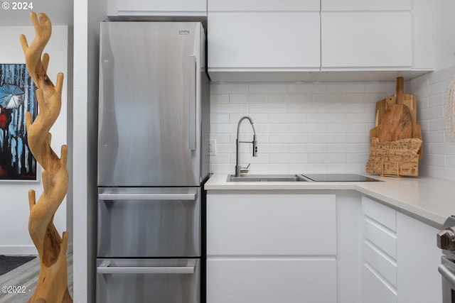 kitchen featuring white cabinetry, stainless steel fridge, tasteful backsplash, and sink