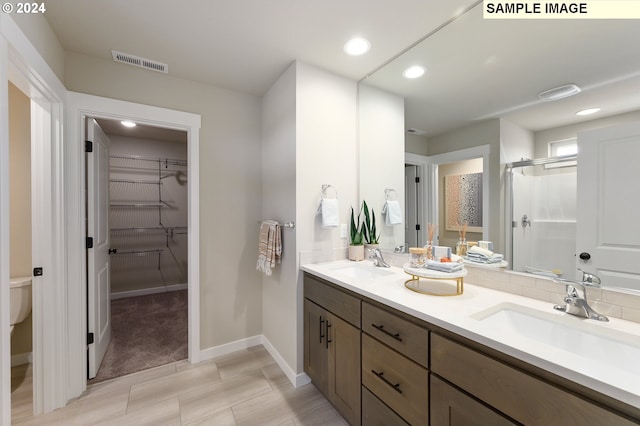 bathroom with vanity, a shower with shower door, and toilet