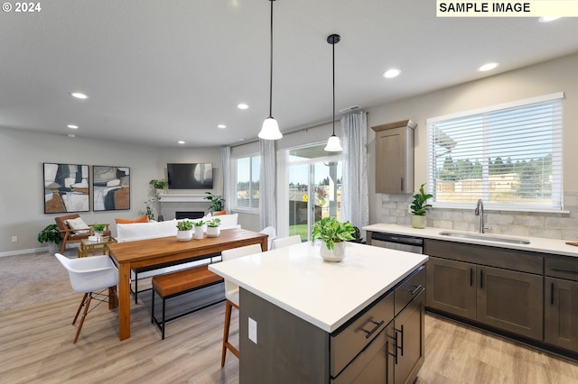 kitchen with sink, a kitchen island, light hardwood / wood-style floors, and decorative light fixtures