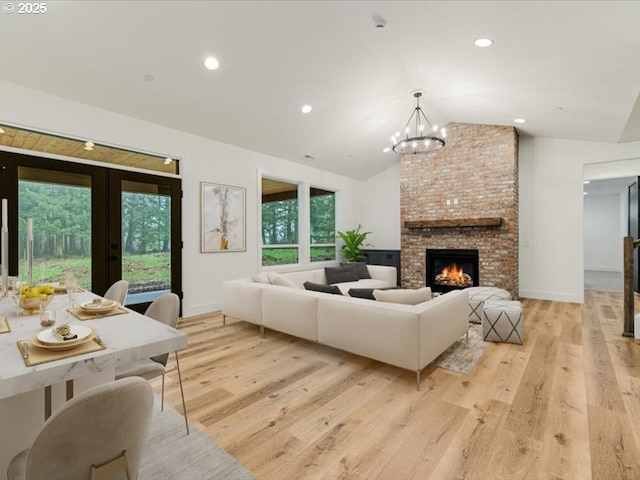 living room featuring a fireplace, a wealth of natural light, light hardwood / wood-style flooring, and vaulted ceiling