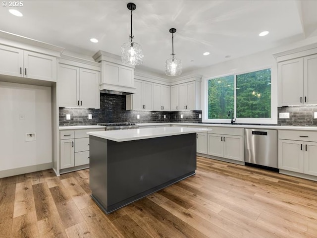 kitchen with dishwasher, a center island, white cabinetry, hanging light fixtures, and light wood-type flooring