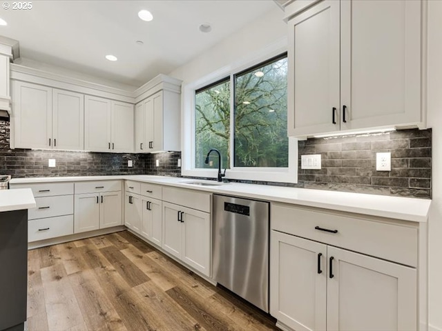 kitchen with dishwasher, decorative backsplash, sink, white cabinetry, and light wood-type flooring