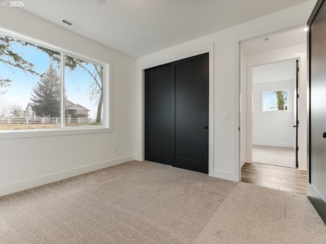 unfurnished bedroom featuring light carpet and a closet