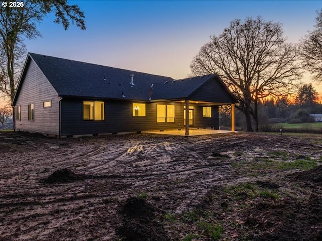 back house at dusk featuring a patio area