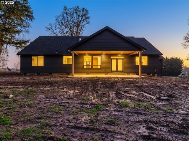 back house at dusk featuring a patio