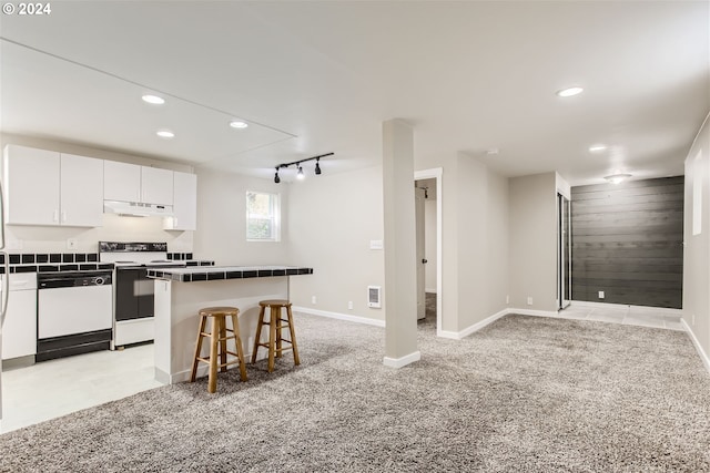 5108 NE Glisan St, Portland, OR 97213 - kitchen with white appliances, under cabinet range hood, a kitchen bar, white cabinets, and light colored carpet