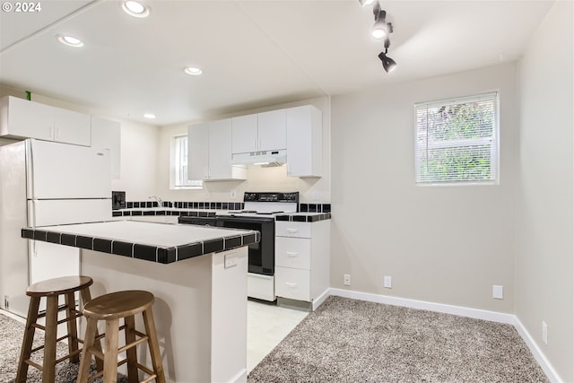 kitchen featuring light carpet, white appliances, white cabinets, tile counters, and a breakfast bar area