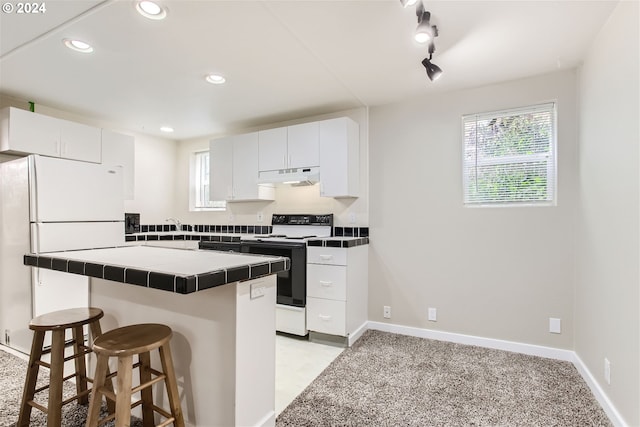 5108 NE Glisan St, Portland, OR 97213 - kitchen with electric range oven, tile counters, under cabinet range hood, freestanding refrigerator, and a kitchen breakfast bar