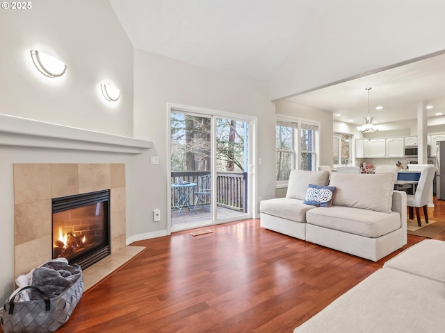 living room featuring a fireplace, light hardwood / wood-style flooring, a notable chandelier, and lofted ceiling