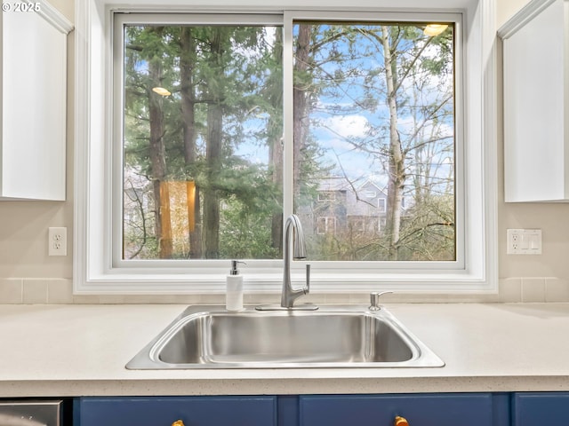 kitchen with sink, dishwasher, plenty of natural light, and blue cabinets