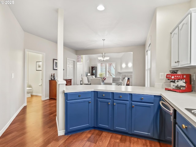 kitchen featuring blue cabinets, kitchen peninsula, dark wood-type flooring, and stainless steel dishwasher