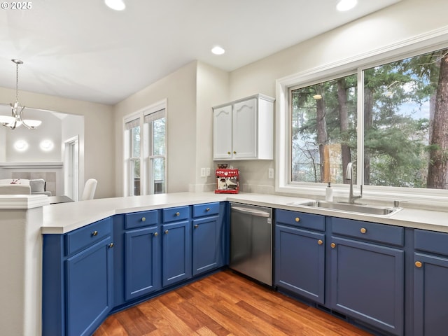 kitchen with kitchen peninsula, stainless steel dishwasher, sink, decorative light fixtures, and blue cabinetry