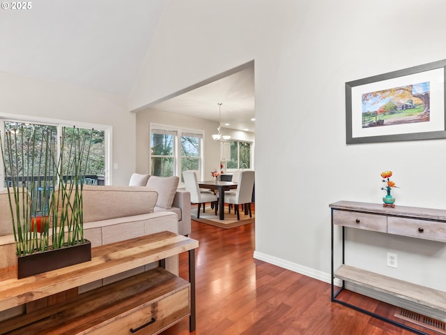 living room featuring wood-type flooring, vaulted ceiling, and an inviting chandelier