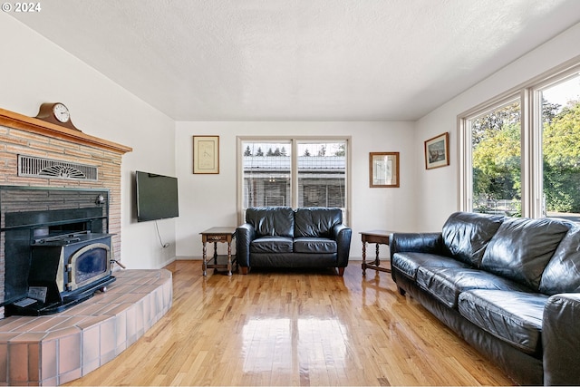 living area with a wood stove, light wood finished floors, visible vents, and baseboards