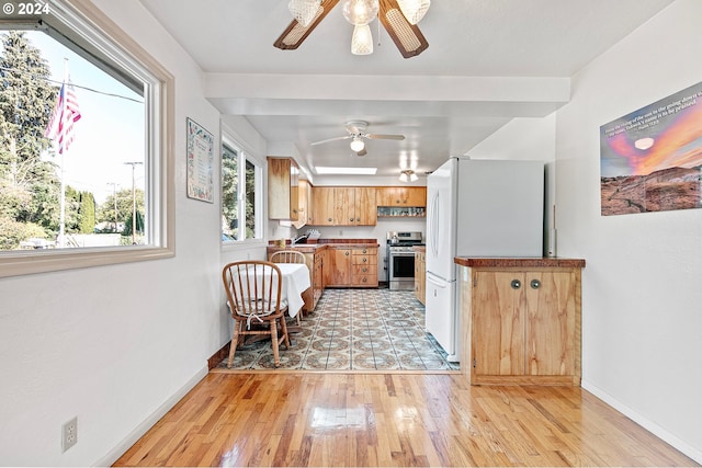 kitchen featuring stainless steel stove, sink, white refrigerator, light hardwood / wood-style floors, and ceiling fan