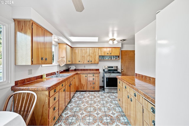 kitchen featuring stainless steel range with gas stovetop, a skylight, plenty of natural light, and sink