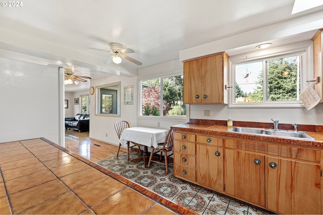 kitchen with light tile patterned flooring, ceiling fan, brown cabinets, and a sink