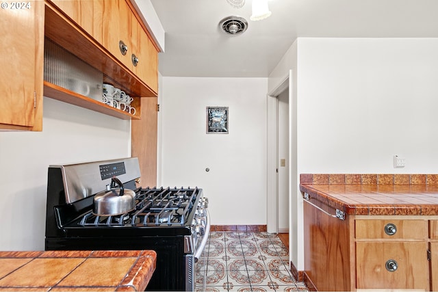 kitchen featuring stainless steel gas stove, light tile patterned flooring, and tile counters