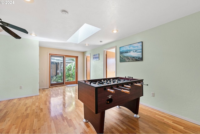 playroom with baseboards, a skylight, a ceiling fan, and light wood-style flooring