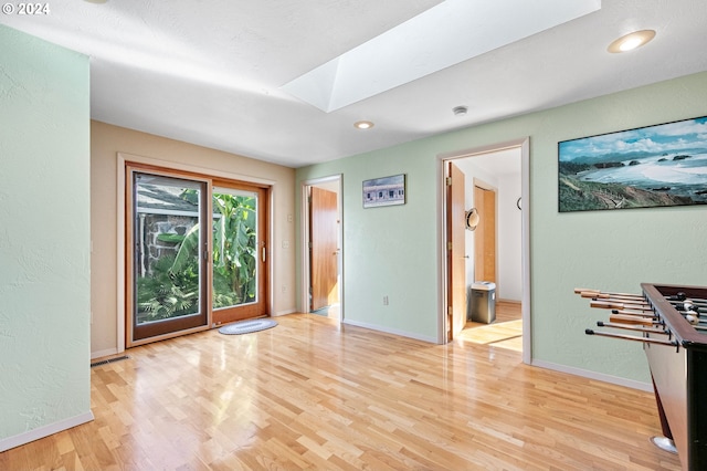 empty room featuring baseboards, recessed lighting, a skylight, and light wood finished floors