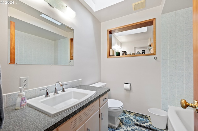 bathroom featuring a skylight, a tub, toilet, tile patterned floors, and vanity