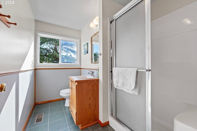 bathroom with toilet, vanity, and a shower with door