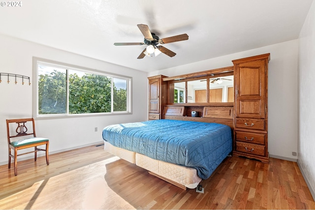 bedroom featuring ceiling fan, light wood-style flooring, and baseboards