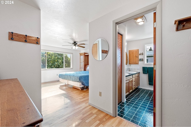 bedroom with sink, ensuite bathroom, light hardwood / wood-style floors, and ceiling fan