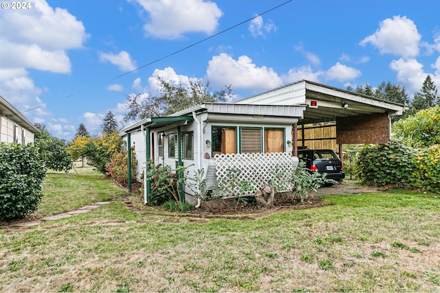 back of property with a carport and a lawn