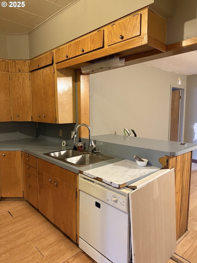 kitchen with kitchen peninsula, dishwasher, sink, and light hardwood / wood-style flooring