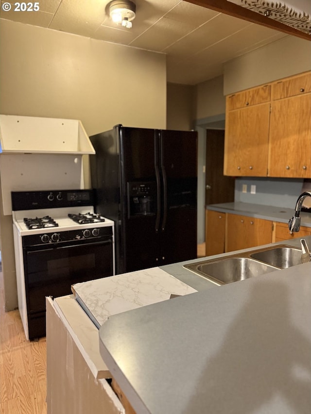 kitchen with black fridge with ice dispenser, white gas range, sink, and light hardwood / wood-style flooring