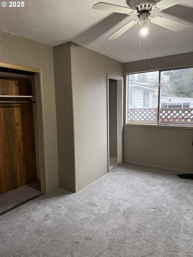 unfurnished bedroom with carpet flooring, ceiling fan, a closet, and a textured ceiling