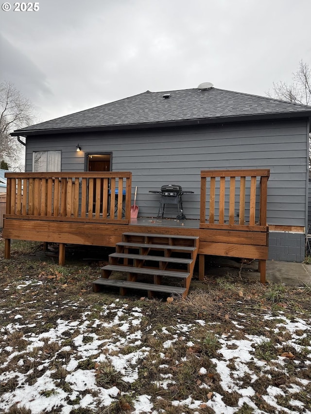 snow covered rear of property with a deck