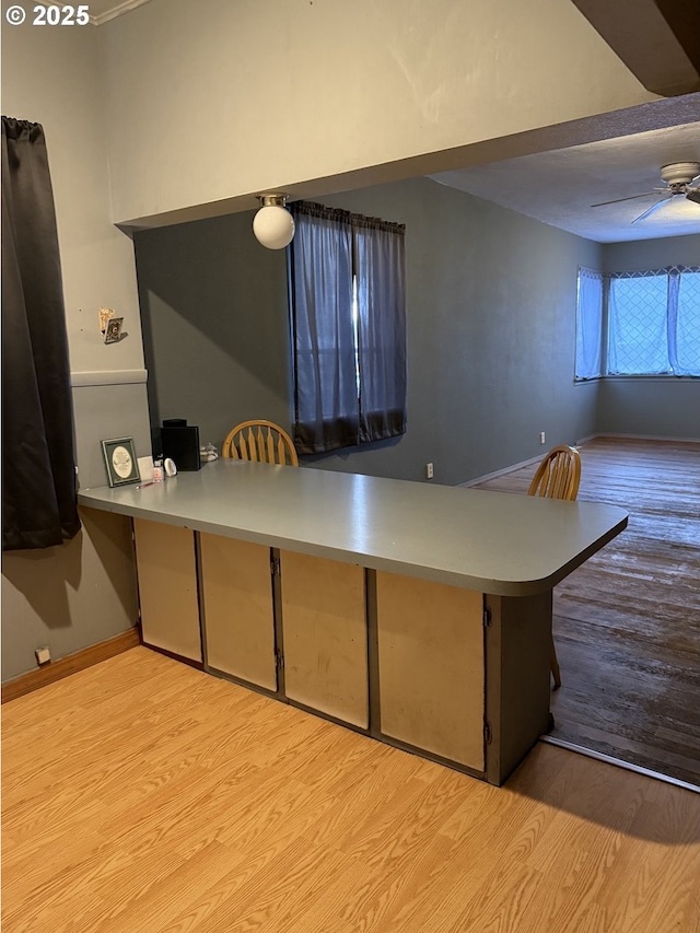 kitchen with kitchen peninsula, light hardwood / wood-style floors, and ceiling fan