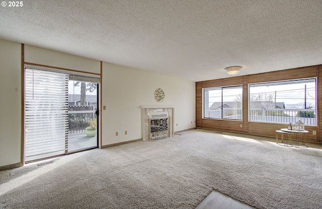 unfurnished living room with a healthy amount of sunlight, visible vents, carpet floors, and a premium fireplace