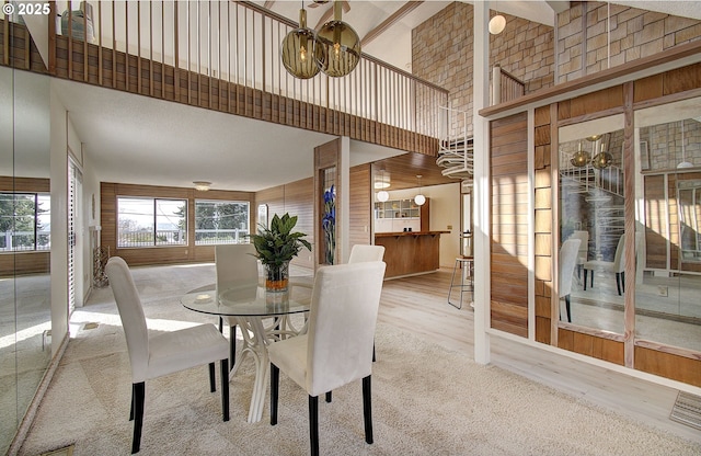 dining room featuring a notable chandelier, wood finished floors, and a towering ceiling