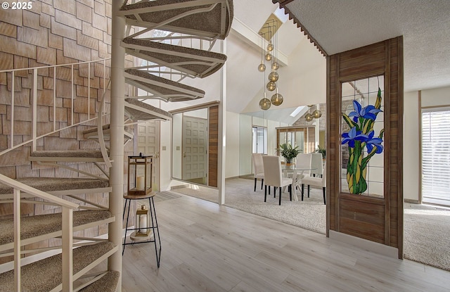 entryway featuring stairs, wood finished floors, a towering ceiling, and a textured ceiling