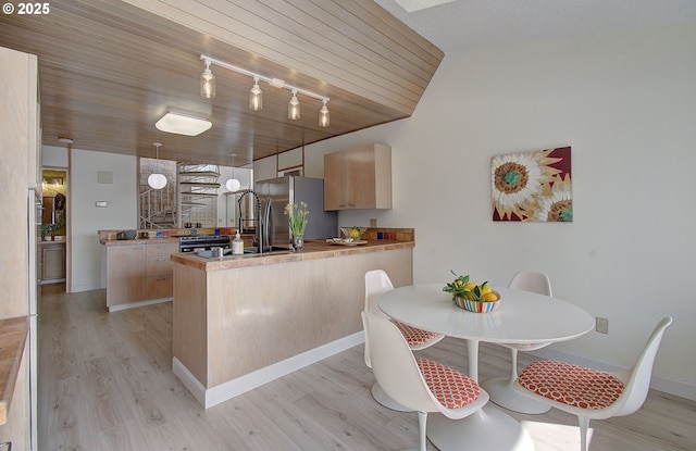 kitchen featuring a peninsula, light wood finished floors, freestanding refrigerator, and light brown cabinetry