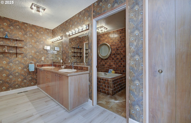 bathroom featuring visible vents, a textured ceiling, wood finished floors, wallpapered walls, and a bath