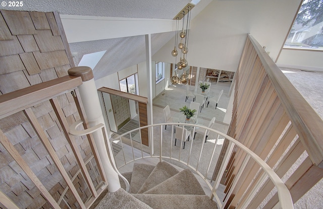 stairs featuring high vaulted ceiling and a textured ceiling