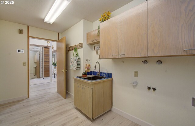 kitchen with baseboards, light wood-style floors, light brown cabinets, and a sink