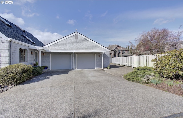 garage featuring concrete driveway and fence