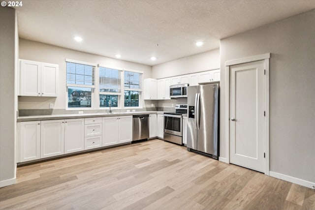 kitchen featuring white cabinets, light hardwood / wood-style floors, sink, and appliances with stainless steel finishes