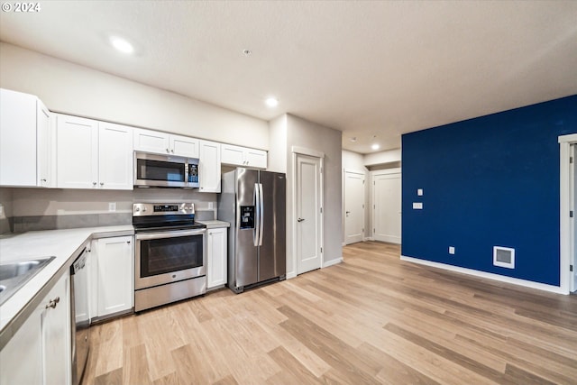 kitchen with white cabinets, appliances with stainless steel finishes, and light wood-type flooring