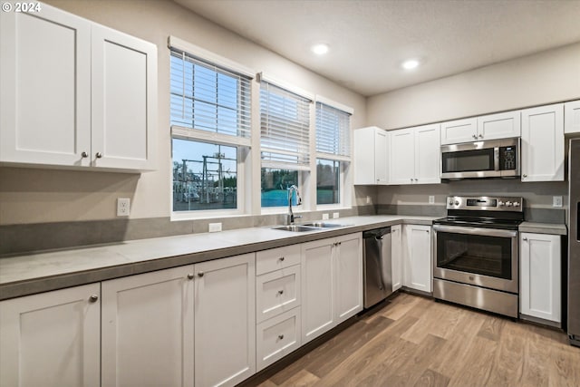 kitchen featuring white cabinets, light wood-type flooring, stainless steel appliances, and sink