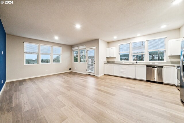 kitchen featuring sink, stainless steel dishwasher, light hardwood / wood-style floors, a textured ceiling, and white cabinets