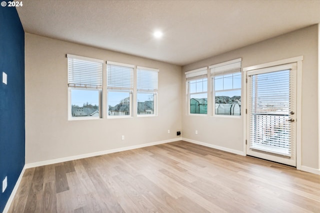 empty room with a textured ceiling and light hardwood / wood-style flooring